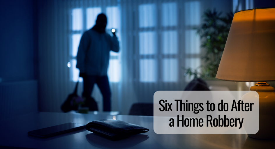 image of burglar entering a person's home, shining a flash light on a phone and wallet on the countertop